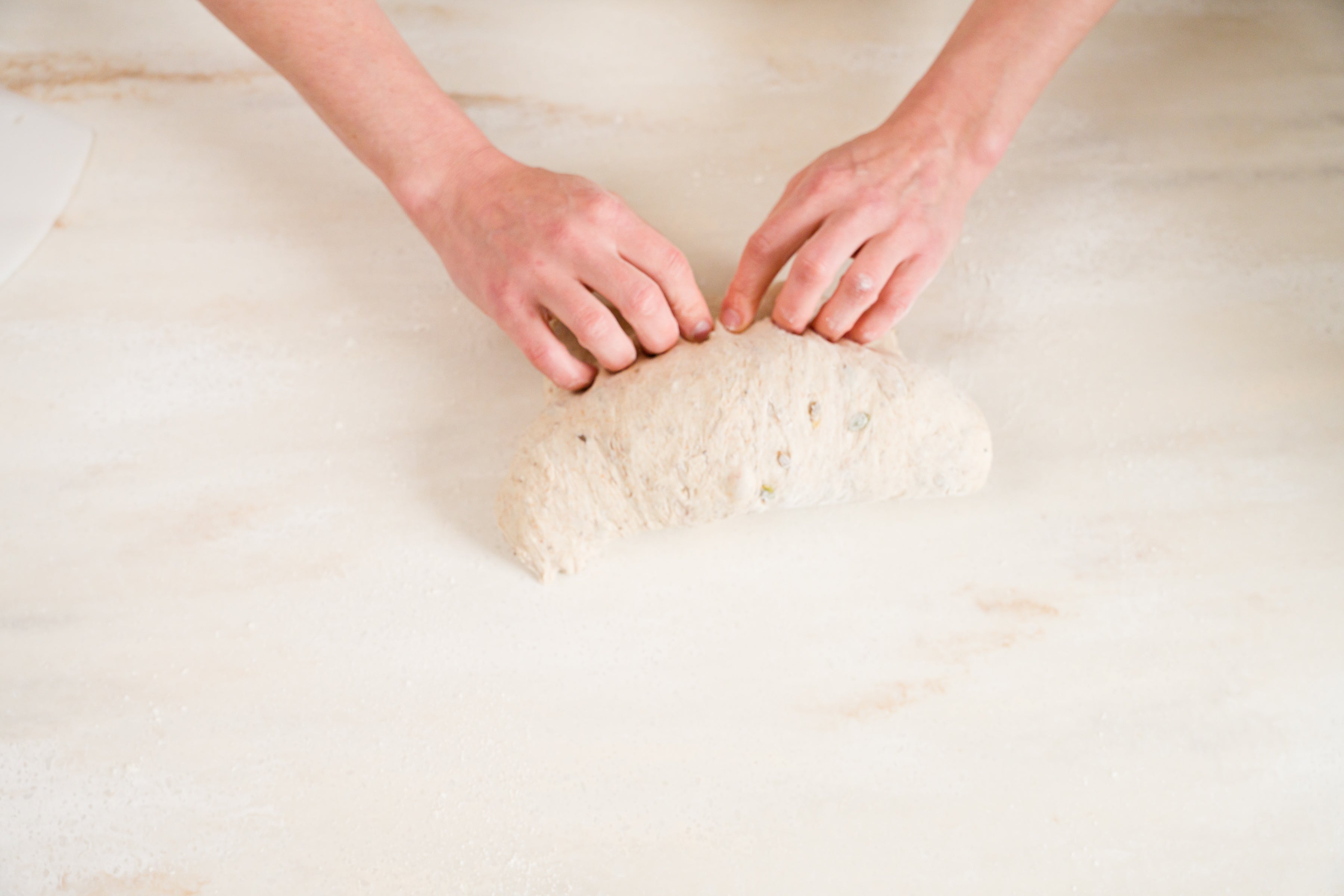 woman's hands pinching seam of shaped bread loaf