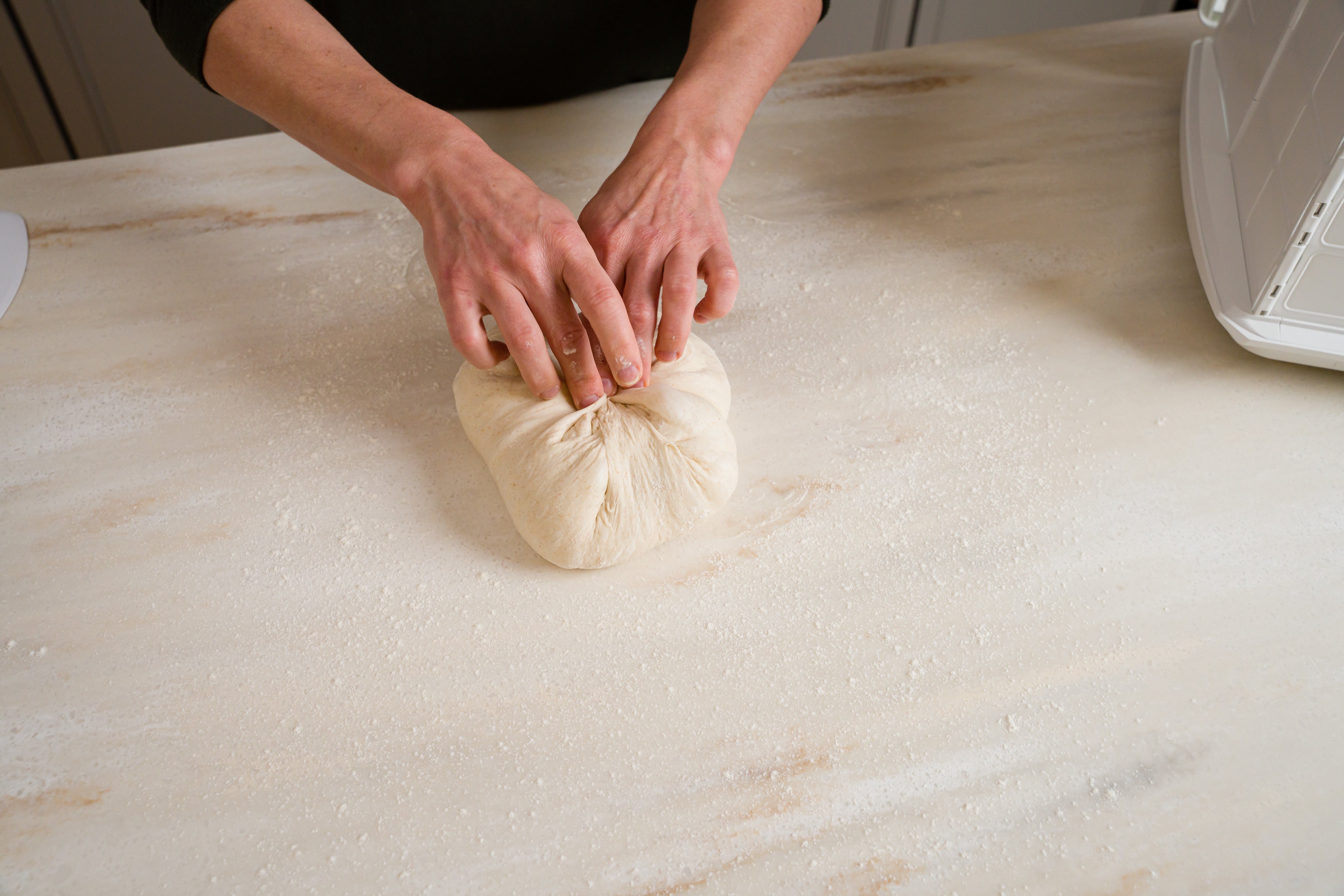 dough on counter being shaped into a round 