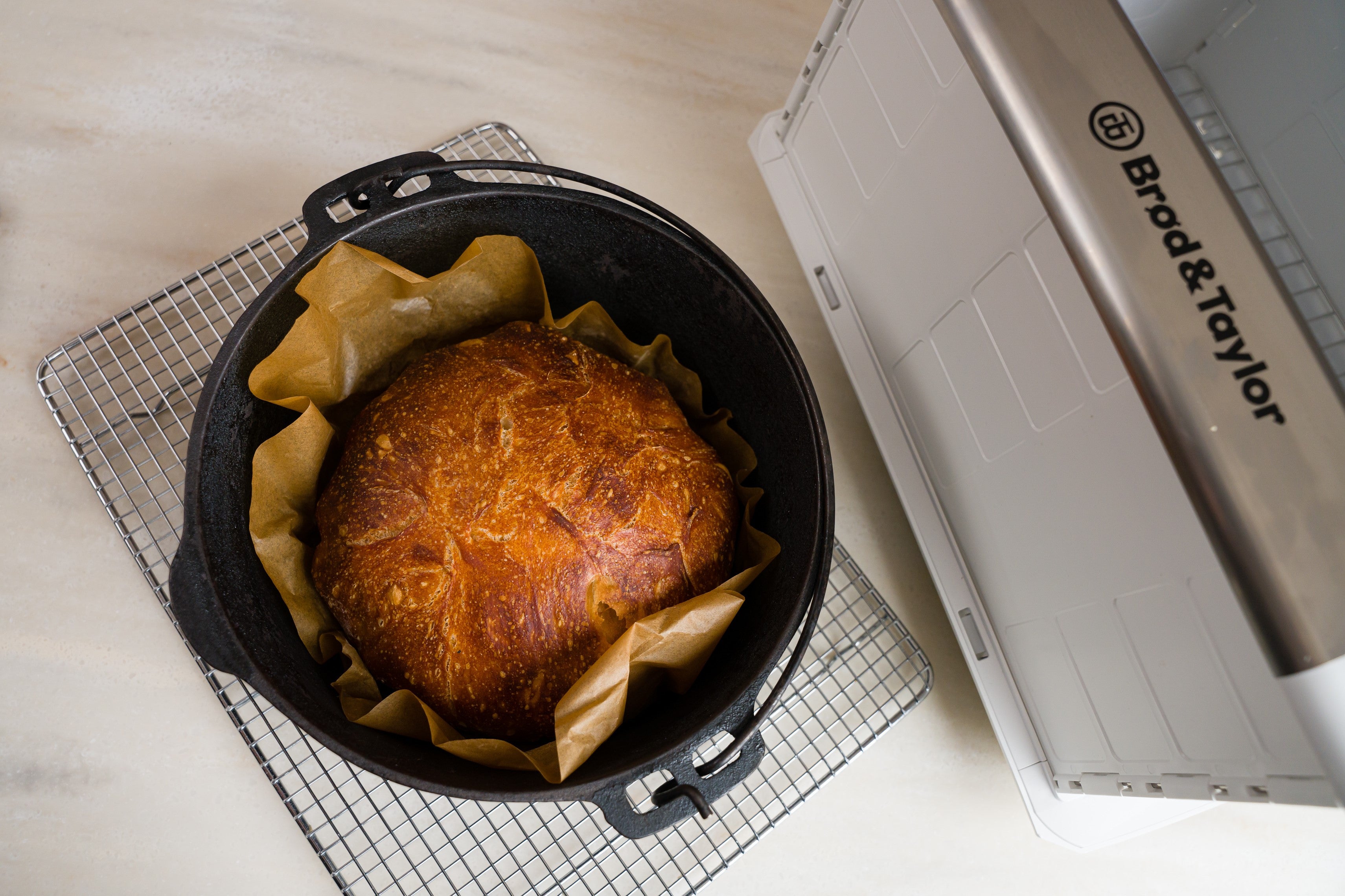 baked no knead bread inside of a cast iron Dutch oven set on a cooling rack