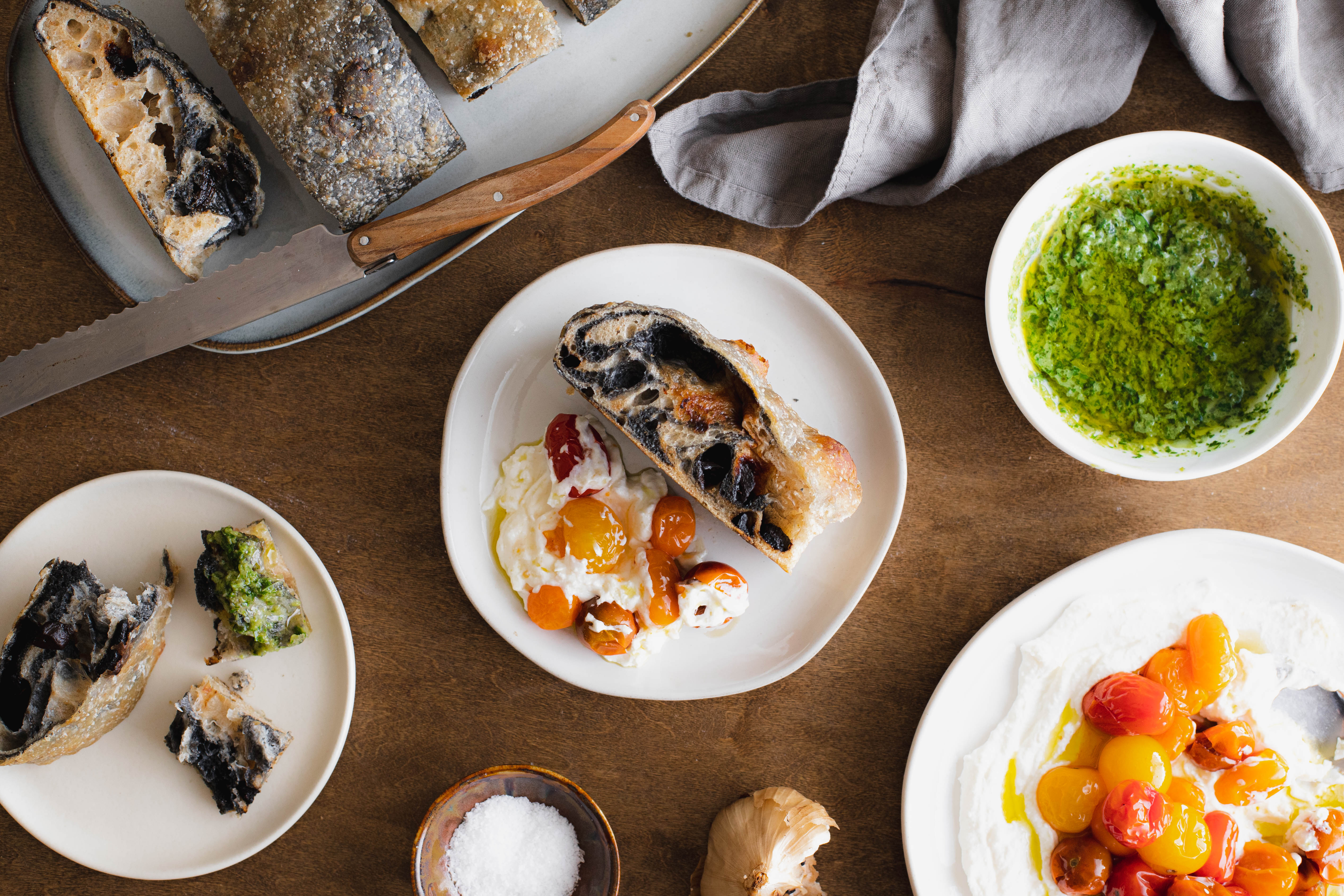 Slice of black garlic focaccia with grape tomatoes and pesto