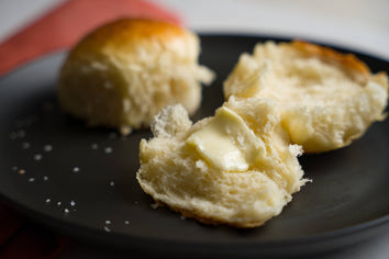 No-Knead Brioche Dinner Rolls, split with butter