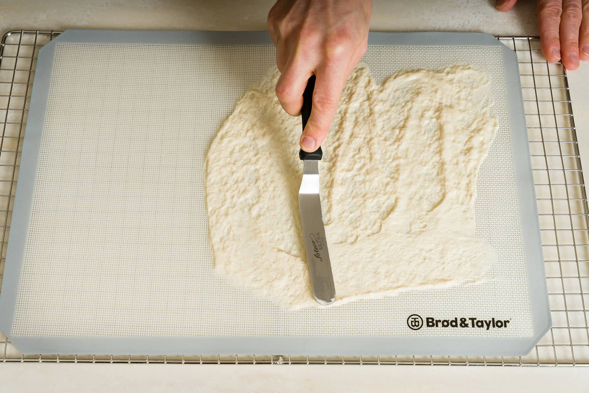 Spreading a thin layer of starter on a silicone mat