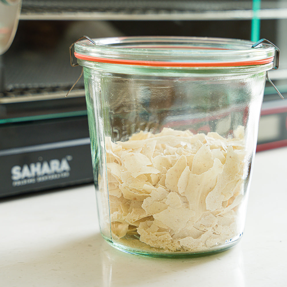 Dehydrated sourdough start in a jar in front of the Sahara Dehydrator