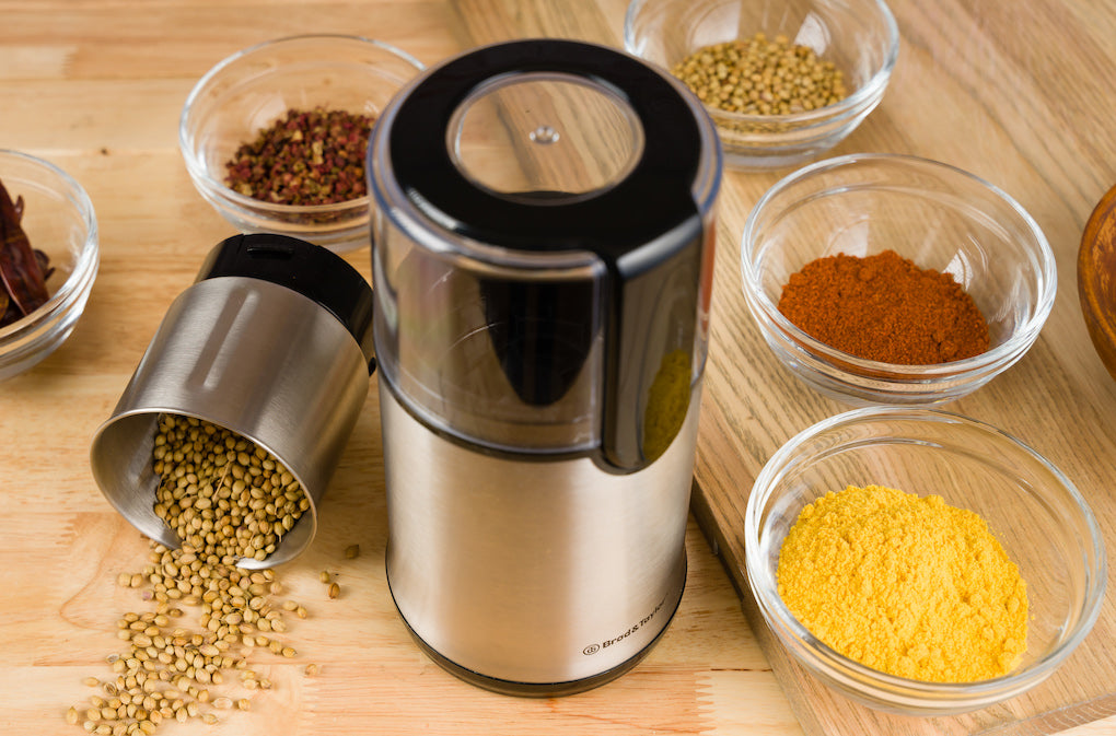 Dried habanero peppers in a grinder in front of Sahara dehydrator and silicon mats