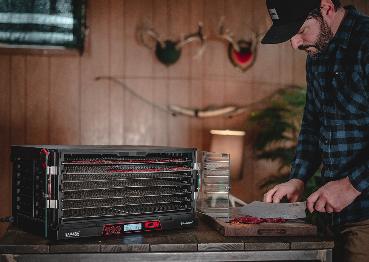 Man cutting beef jerky for dehydrating in rustic home