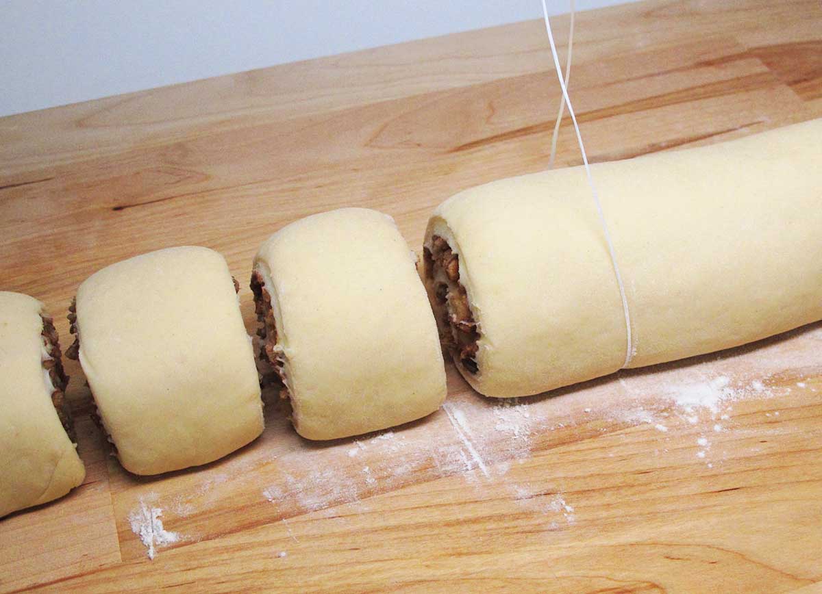 Slicing the rolled cinnamon rolls with string