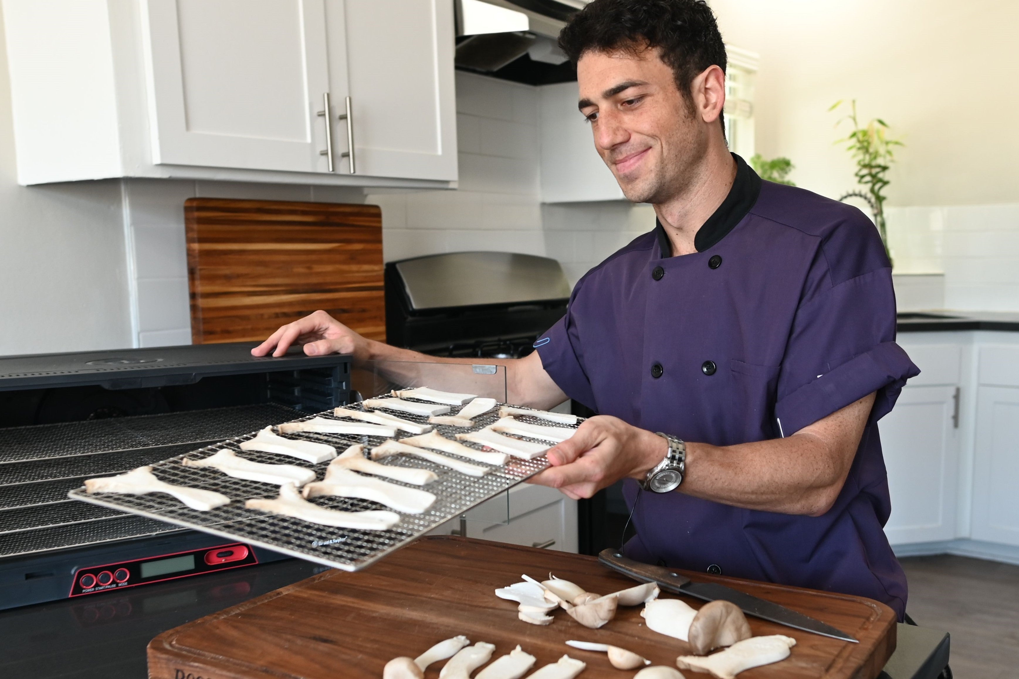 Mario Fabbri plaçant des champignons tranchés dans le déshydrateur pliant Sahara.