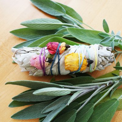 Tied sage and flower smudge surrounded by fresh sage leaves