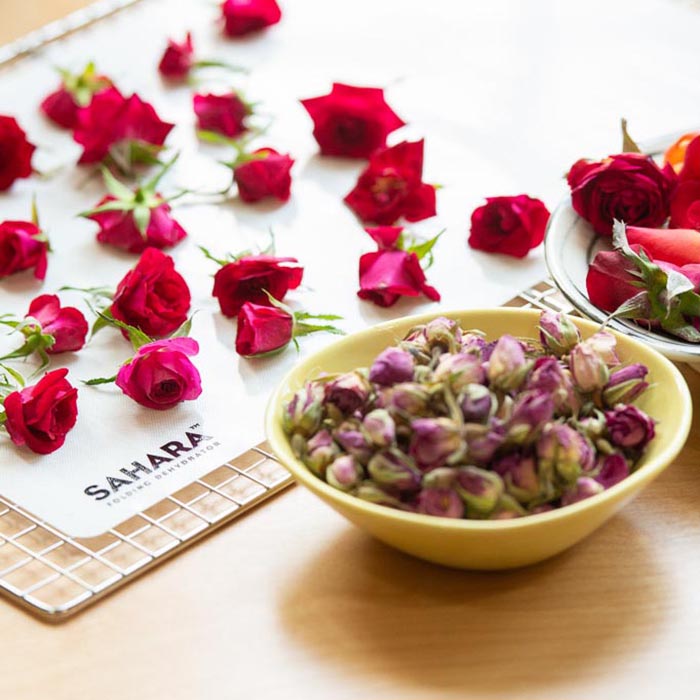 Boutons de rose frais sur un tapis en silicone et boutons de rose déshydratés dans un bol