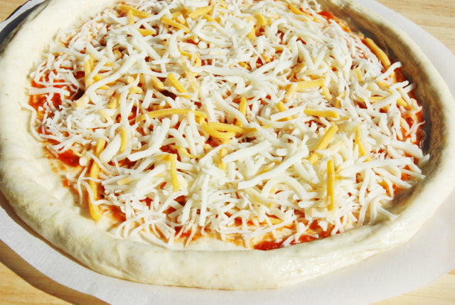 Rustic Pizza topped with cheese before baking