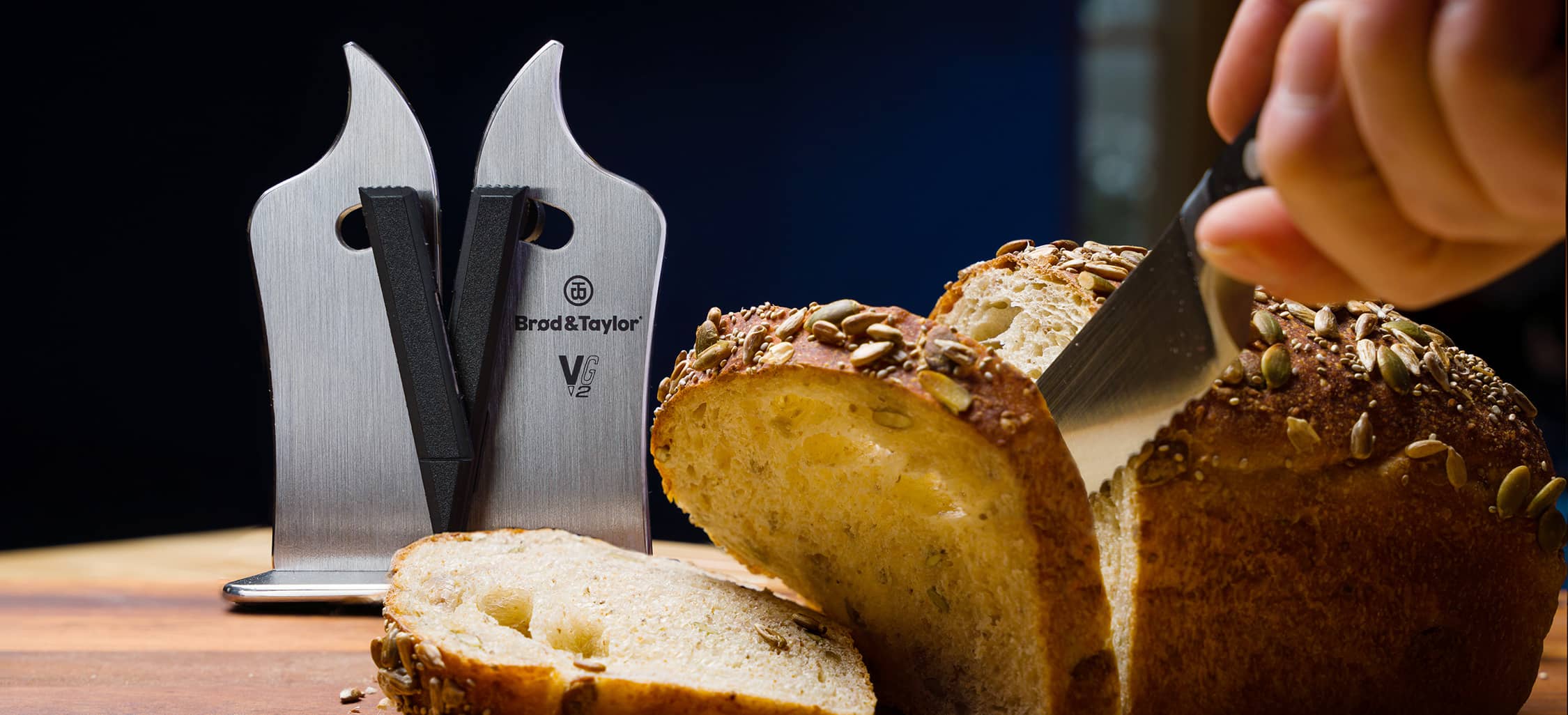 Slicing bread with a bread knife and the Professional VG2 Knife Sharpener in background