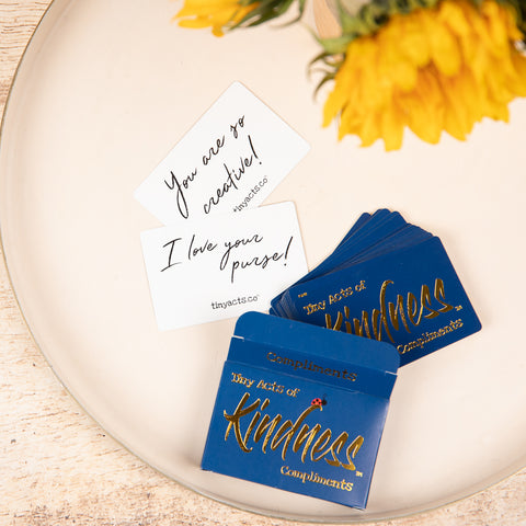 navy blue box with gold kindness text and white cards with black text compliments