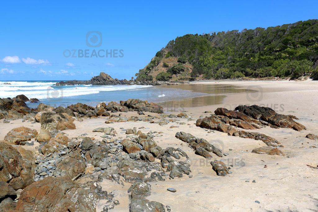 Rusty coloured shoreline against a backdrop of greenery at Kings Beach, Broken Head NSW.