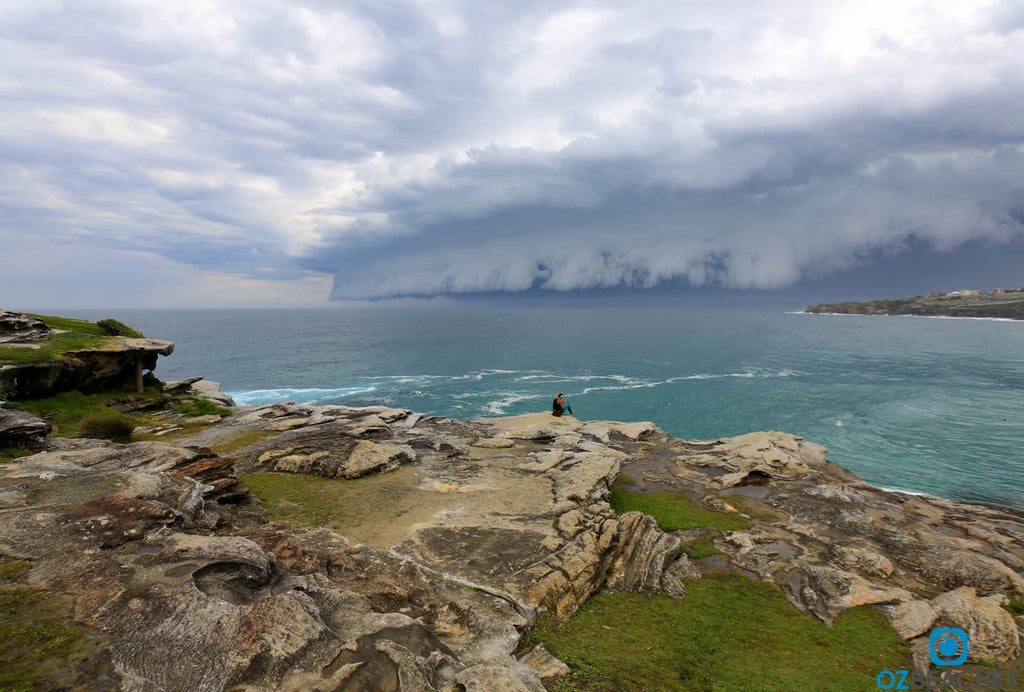 Girl sitting at Tamarama Beach watching a supercell storm approach