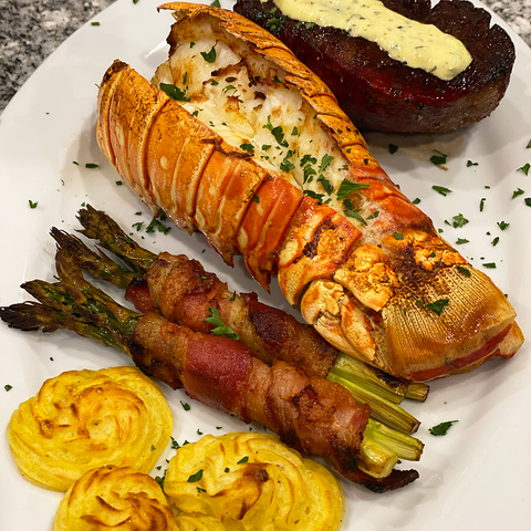 cooked lobster tail with bacon wrapped asparagus and sides