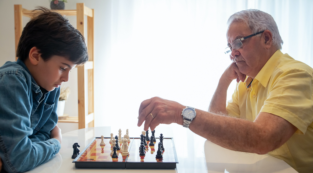 Boy playing chess with his grandpa