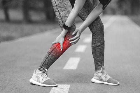 Female athlete with running injury holding lower leg