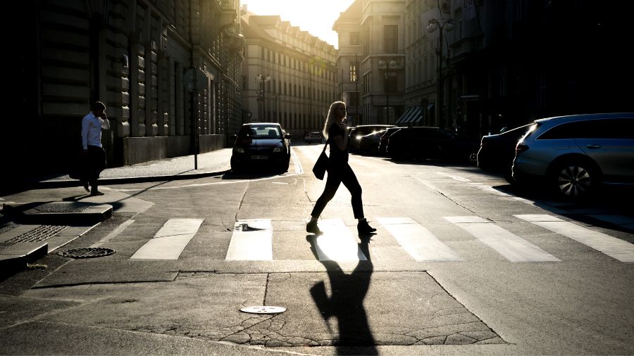 Imagen a contraluz donde se ve una mujer cruzando por un paso para peatones.