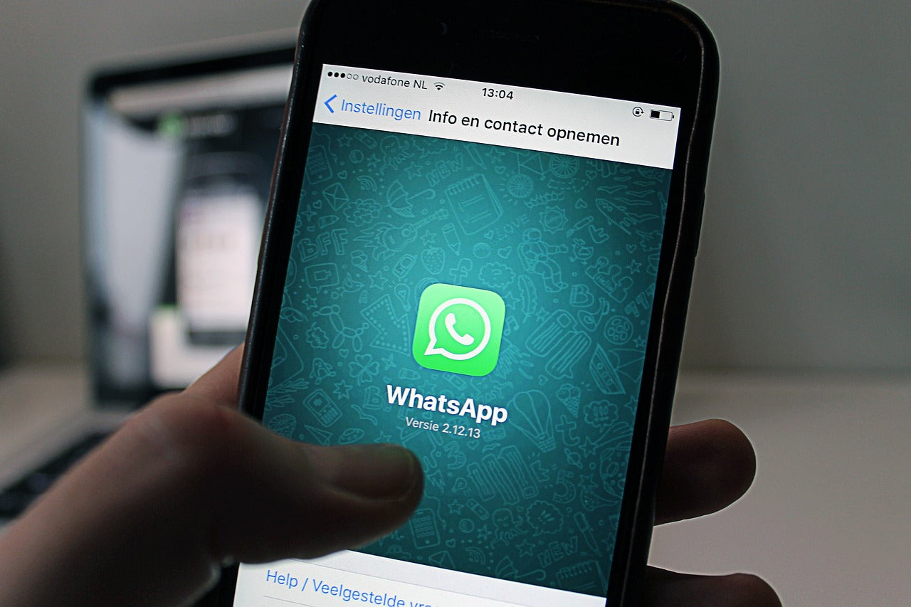 Una mano sostiene un teléfono inteligente que en su pantalla muestra la aplicación WhatsApp.