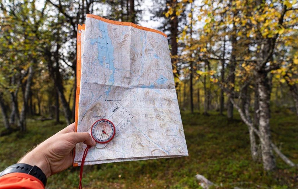 Man explorer searching direction with compass for map