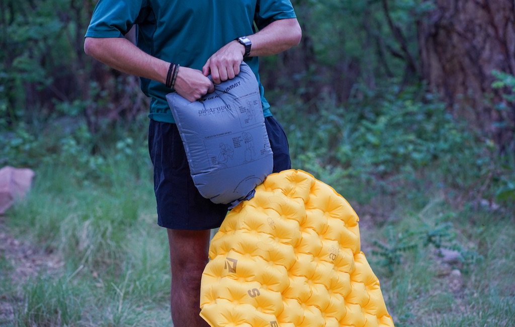 hiker inflating a sleeping pad using an inflation sack