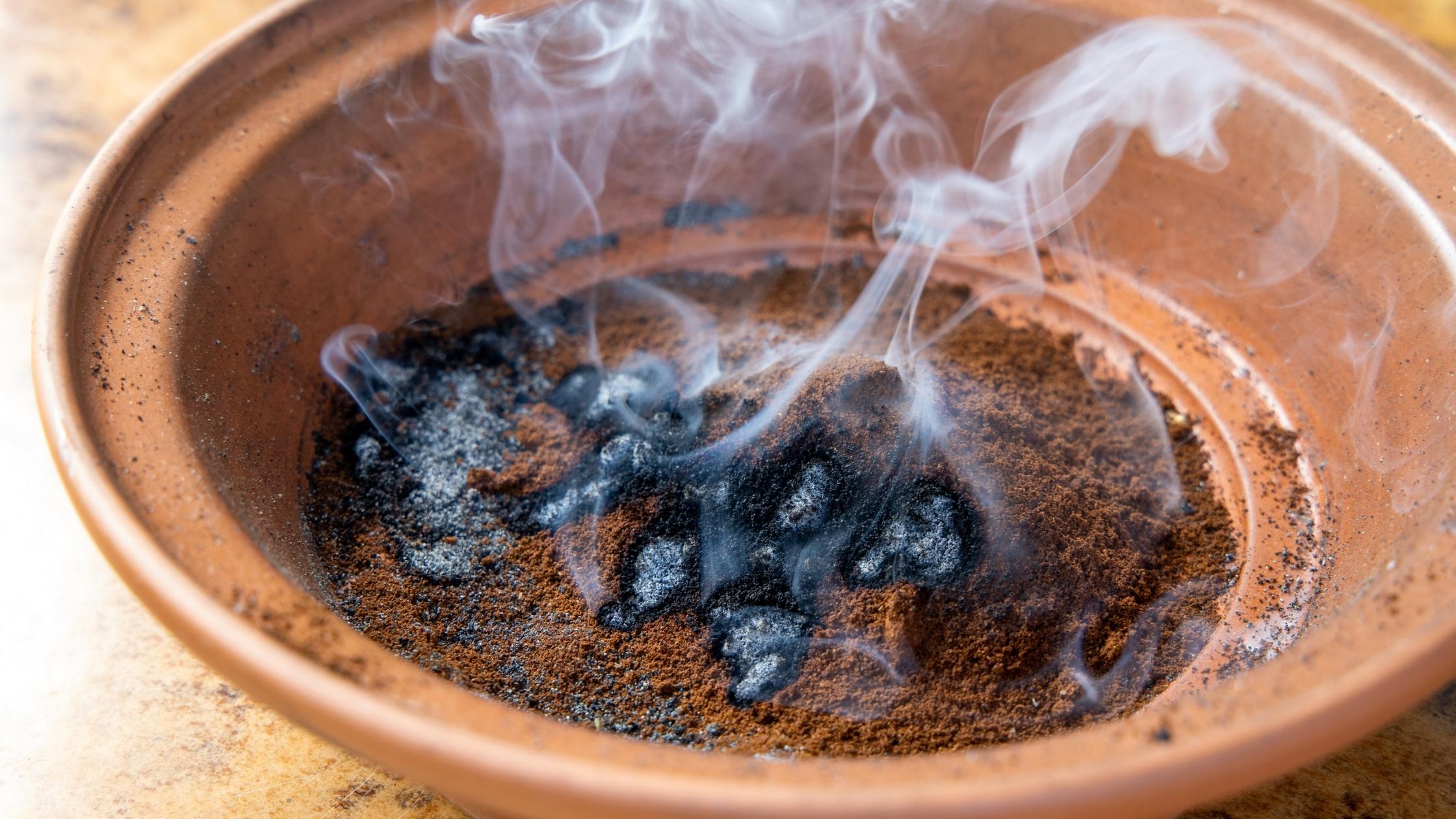 Burning coffee grounds for insect repellent