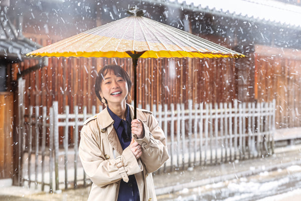 A woman holding a Gifu Japanese umbrella in the snow