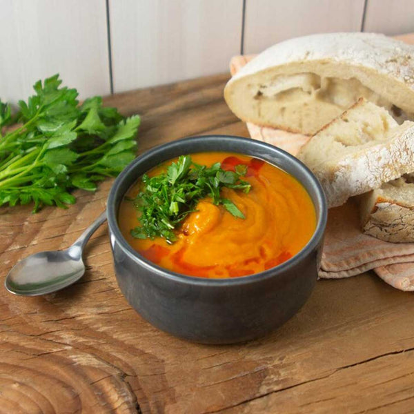 Creamy cauliflower sweet potato soup in a bowl with sliced fresh bread and parsley.