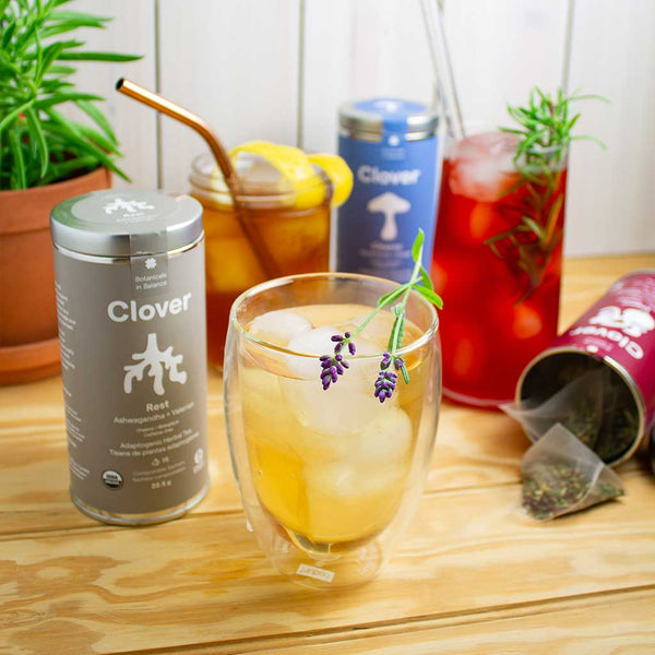 Clover iced tea blends Rest, Digest and Cleanse on a textured wooden surface.