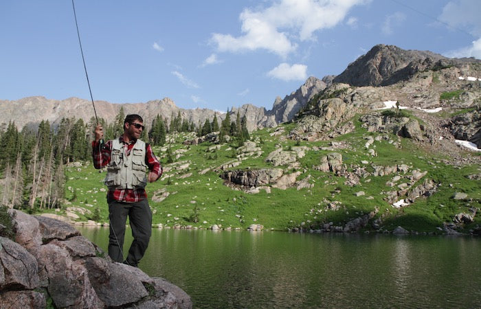 man fishing at a lake in the mountains