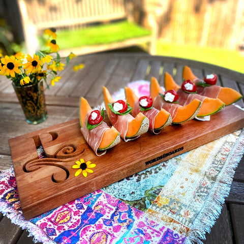 Monogrammed Horizontal Cutting Board with scroll initial cut out on the left. Board pictured is tipped with melon slices.