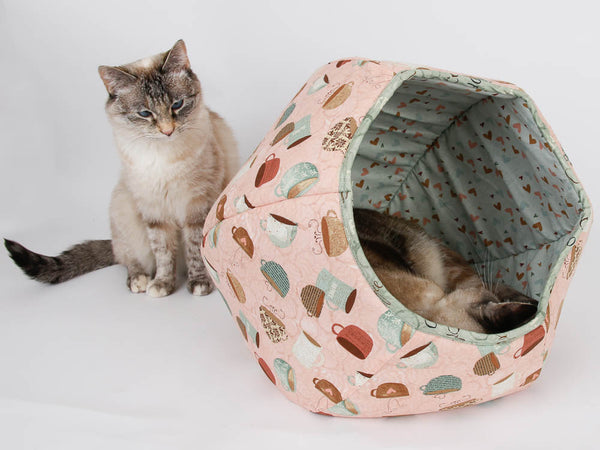 A large cat sleeps inside the Cat Ball® cat bed while a smaller cat watches from outside. 