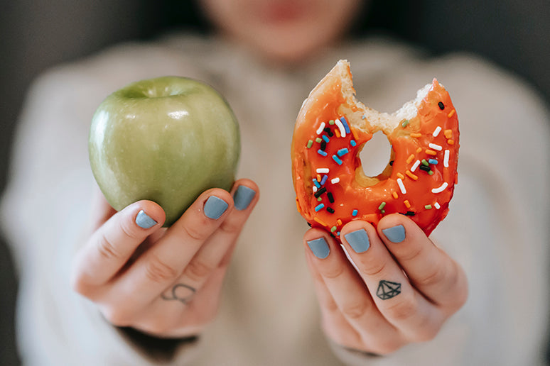Someone holding an apple next to a donut