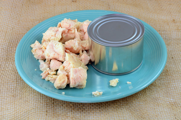 Canned chicken plated on blue plate on burlap mat