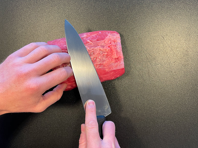 Trimming all external fat from the meat.