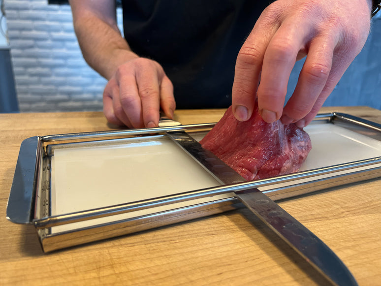 Slicing meat for jerky with a jerky board slicer.