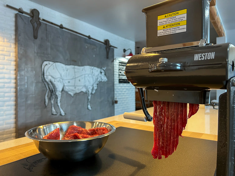 Slicing meat for jerky with a manual crank jerky slicer. 