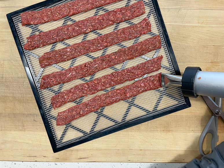 Making ground beef jerky with a jerky gun.