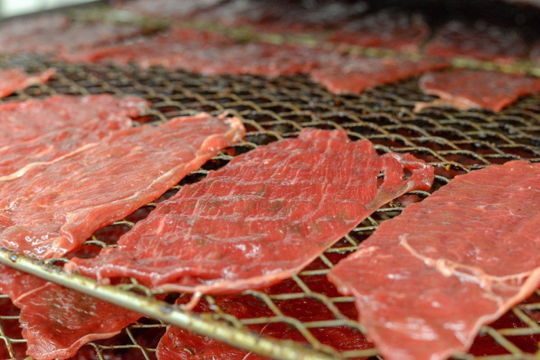 Slabs of raw meat on a rack ready to be cooked.