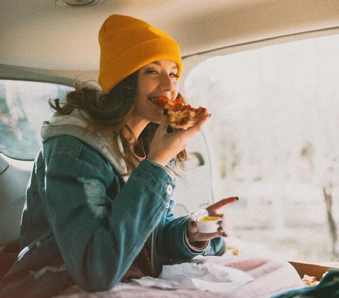 Woman eating pizza in the car