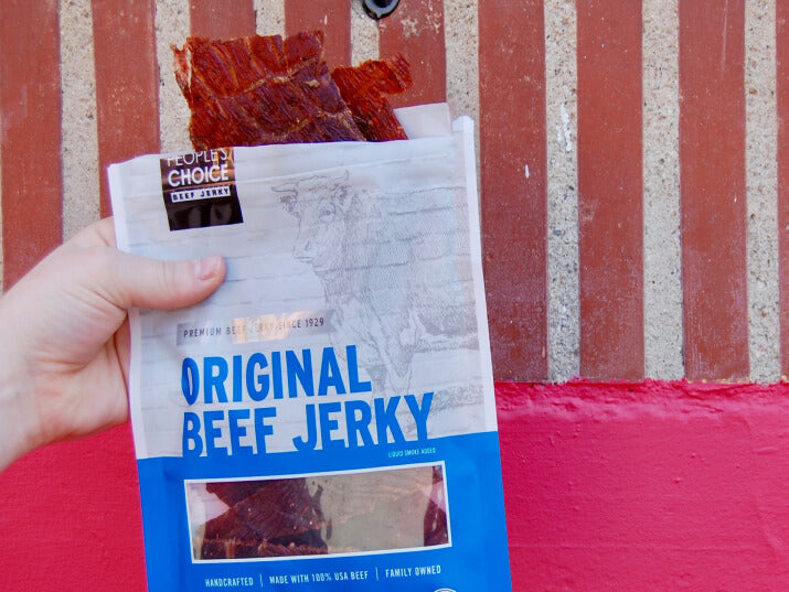 Photo of persons hand holding a bag of beef jerky