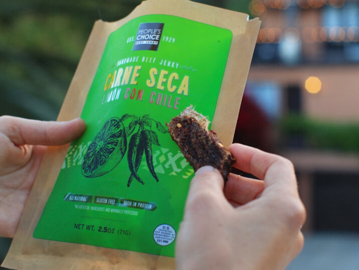 Photo of persons hand holding a bag of beef jerky