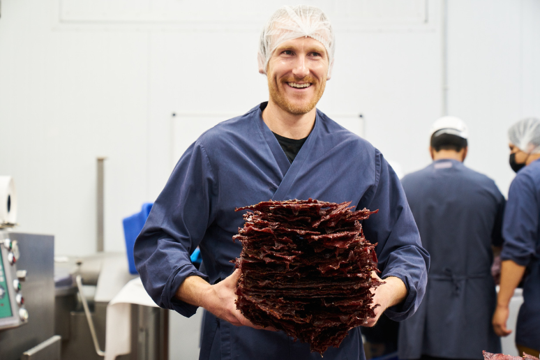 Brian carrying a big stack of jerky slabs in production.