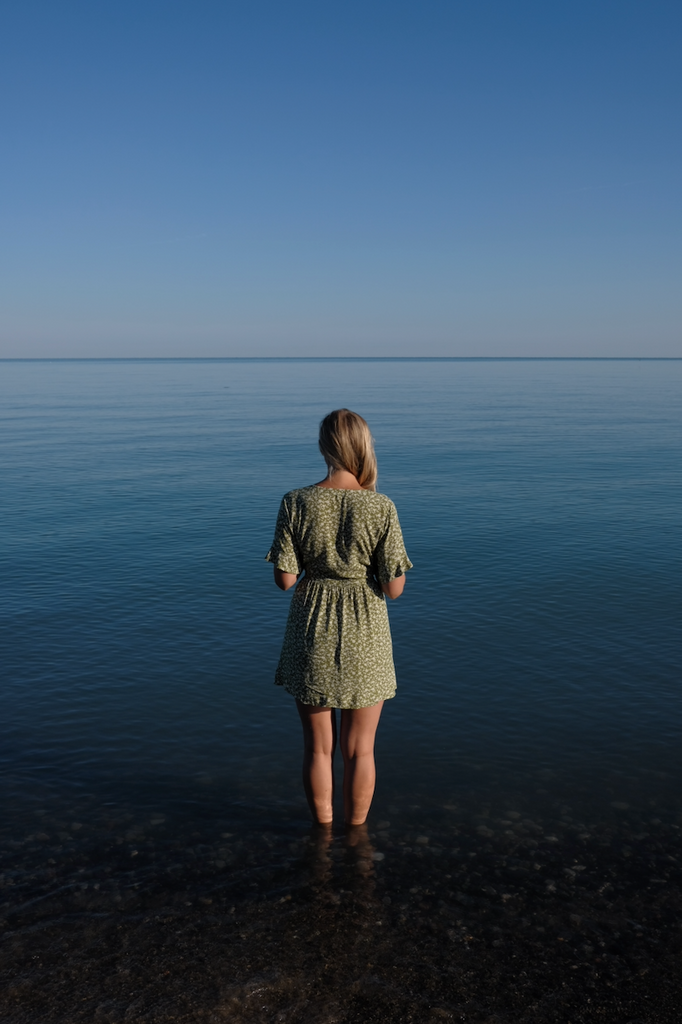 woman standing in front of calm lake luron silhouette sunrise