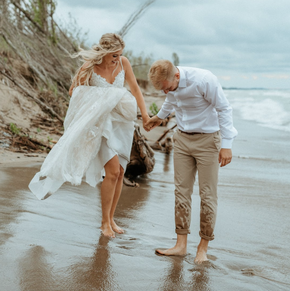 Newlywed couple at beach being splashed by the waves