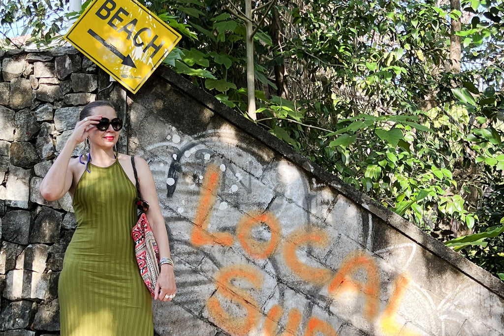 Dorian in Phuket wearing a green dress in front of a sign for the beach