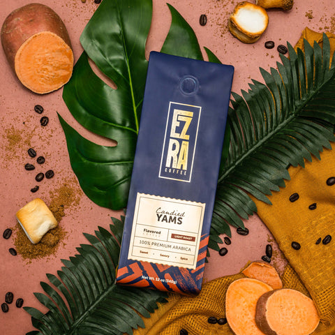Bag of Candied Yams Blend by Ezra Coffee Co. amidst decorative palm fronds, sliced yams, and coffee beans.