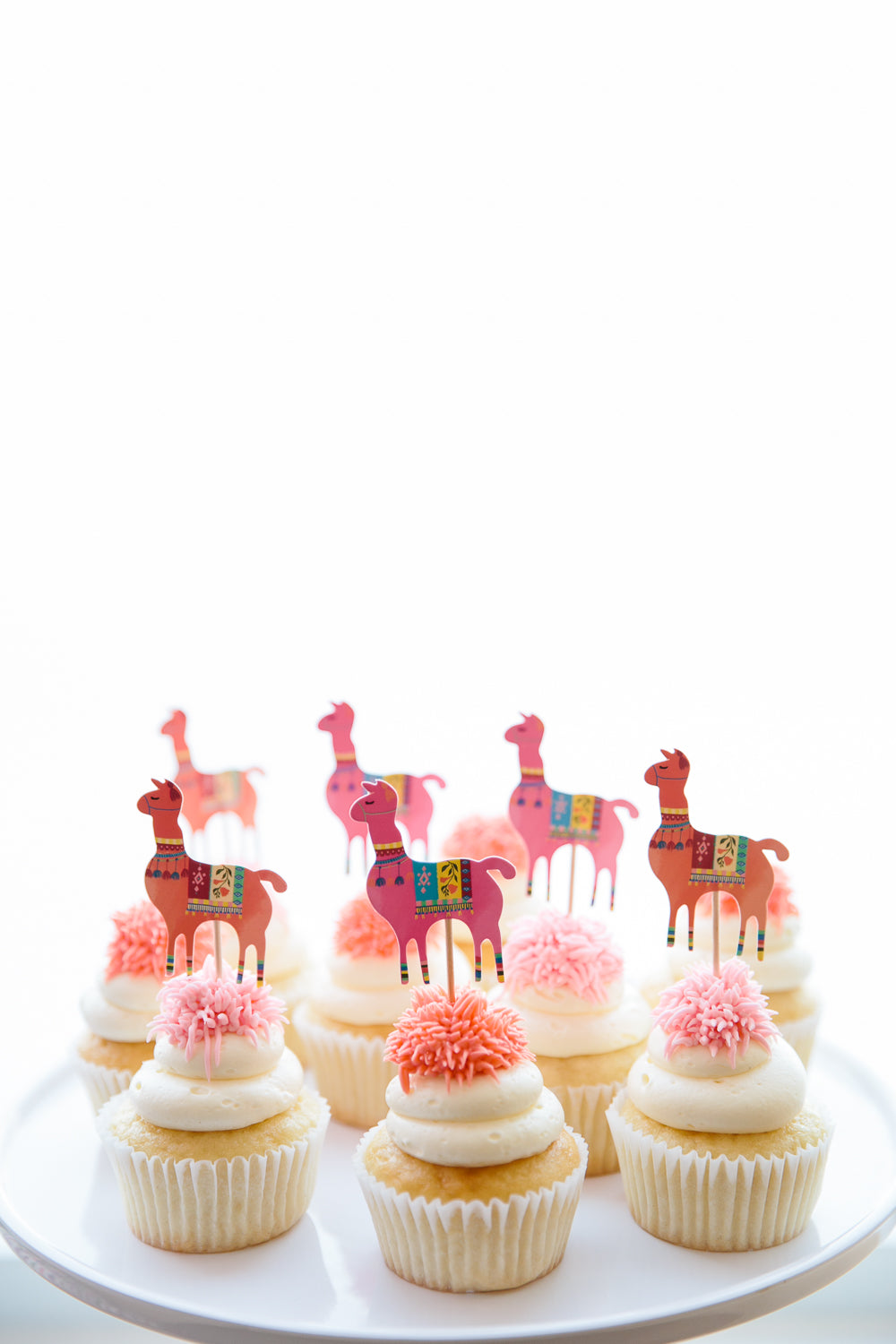 Cupcakes topped with llama food picks for a fun Cinco de Mayo dessert. 