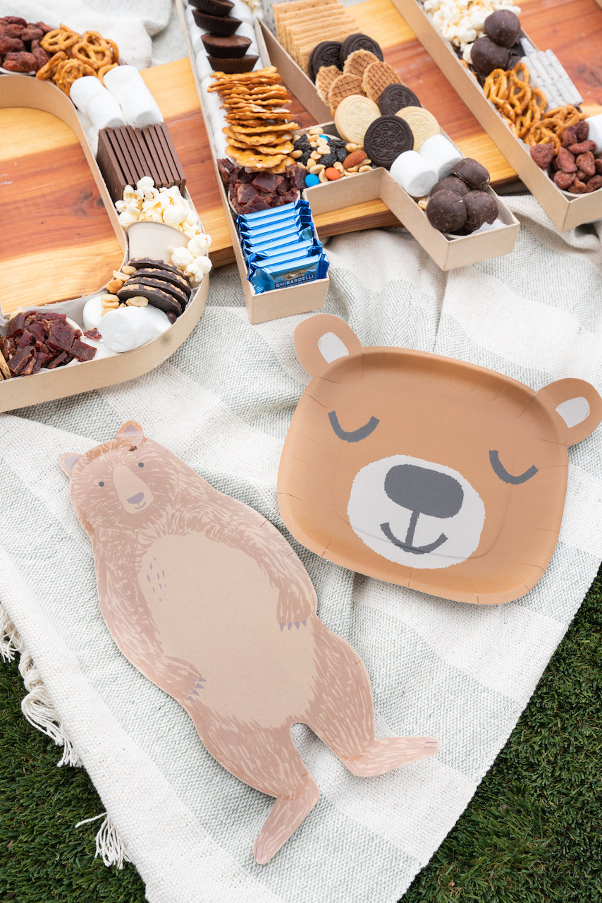 Bear plates and napkins set out for a kid's camping-themed birthday party.