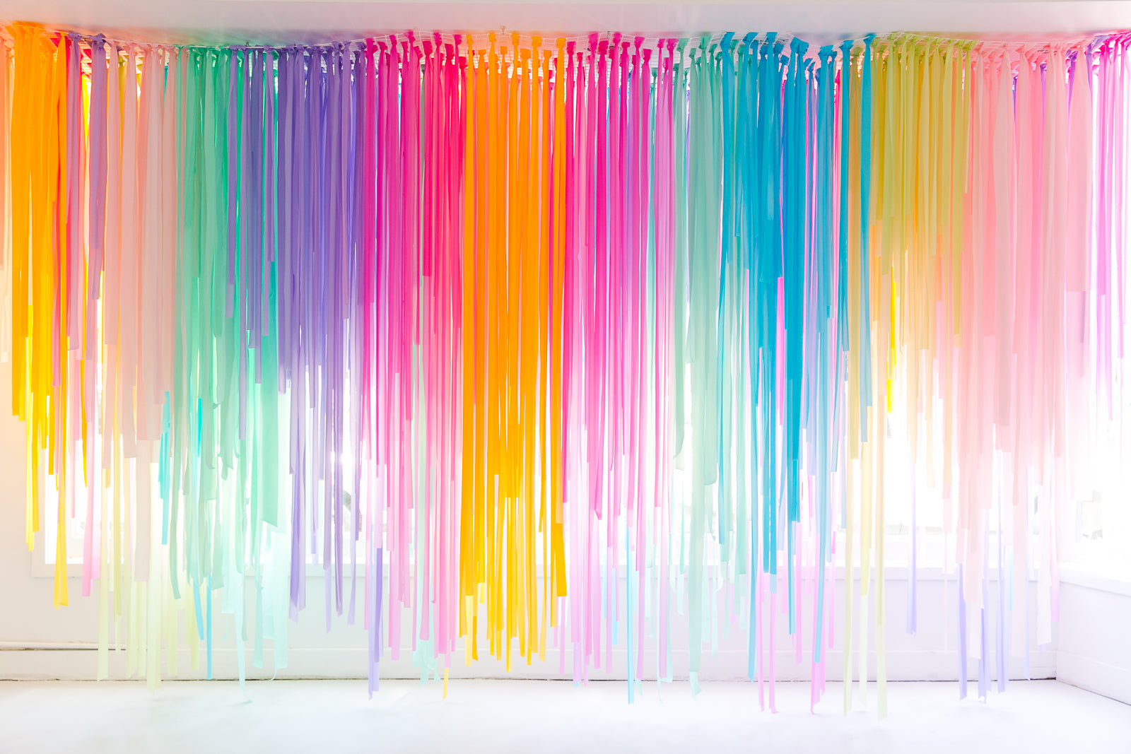 Rainbow party backdrop using rainbow streamer decorations.